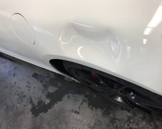 Sichtbarer Karosserieschaden Beschädigter hinterer Kotflügel eines Porsche mit Karosseriedelle